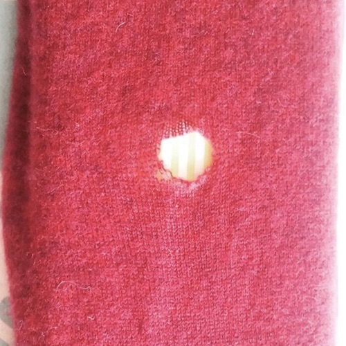 Loch in Strickpullover vor dem Kunststopfen